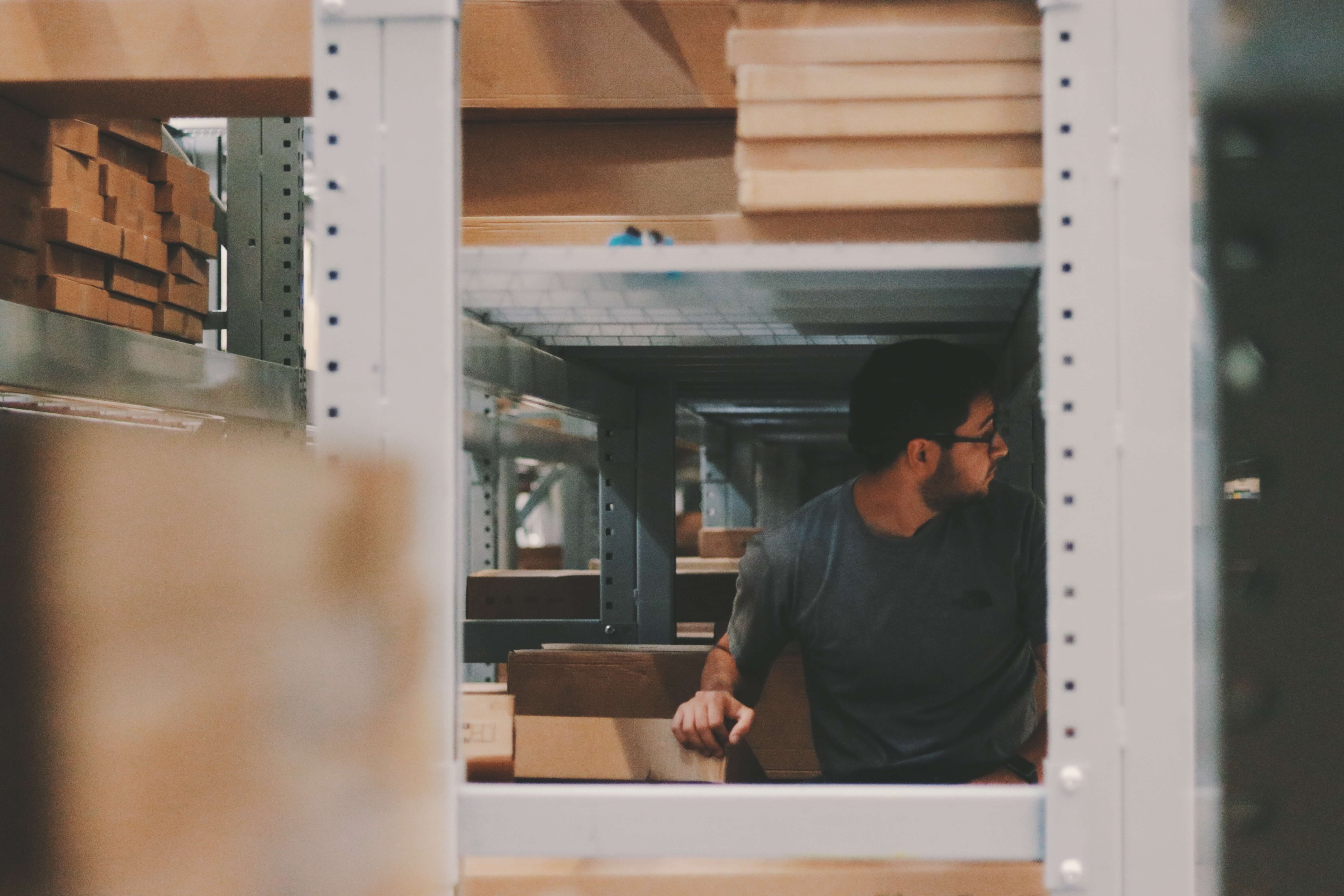 Man sitting under shelves filled with packaging