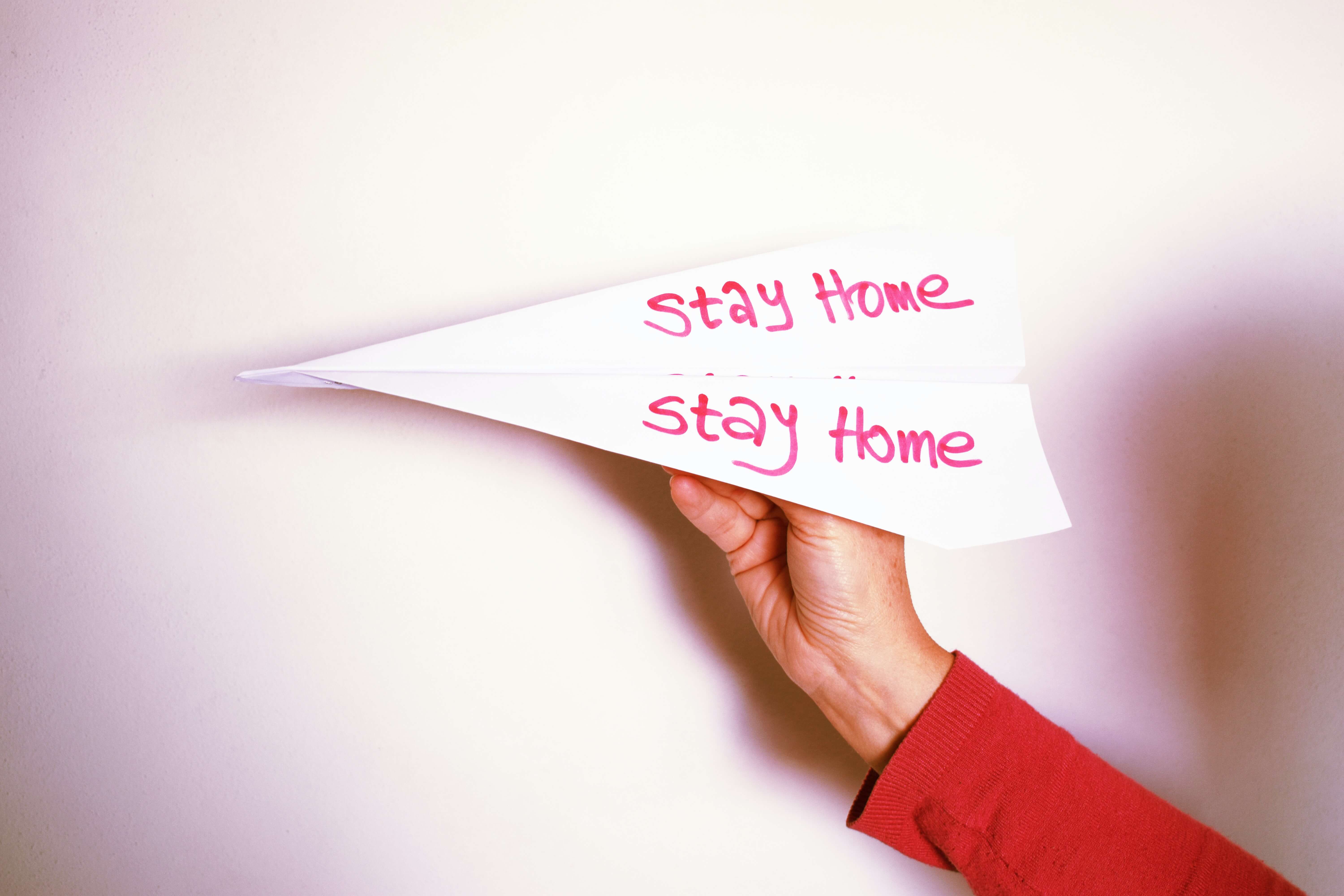 hand holding paper plane saying stay home