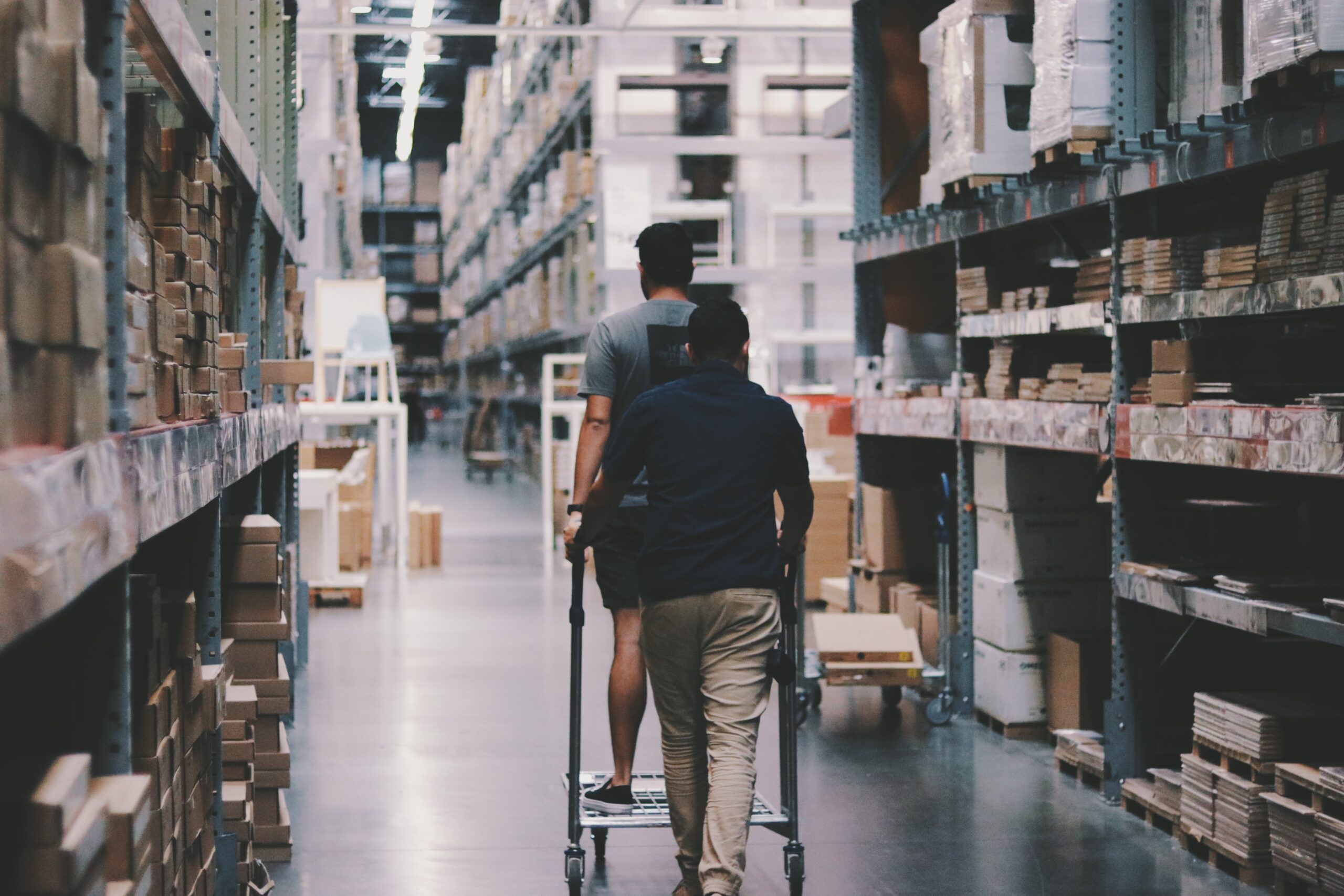 a man in a huge warehouse with parcels riding on a goods cart